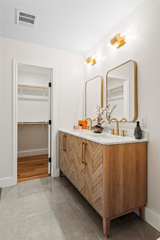 6303 Bexton Cir, Austin, TX 78745 - bathroom featuring double vanity, a spacious closet, baseboards, and tile patterned floors