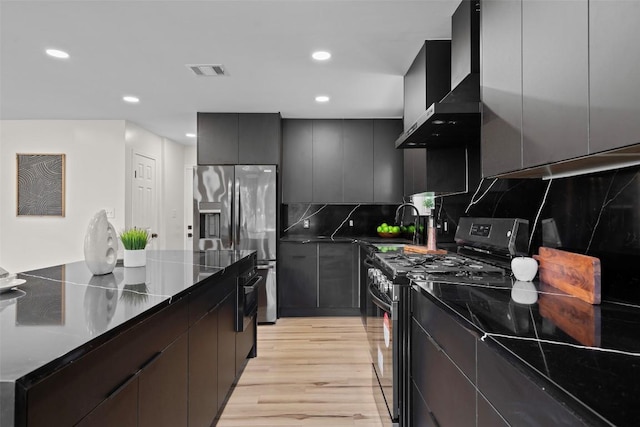 6303 Bexton Cir, Austin, TX 78745 - kitchen featuring black gas range, stainless steel fridge with ice dispenser, wall chimney exhaust hood, light wood finished floors, and tasteful backsplash