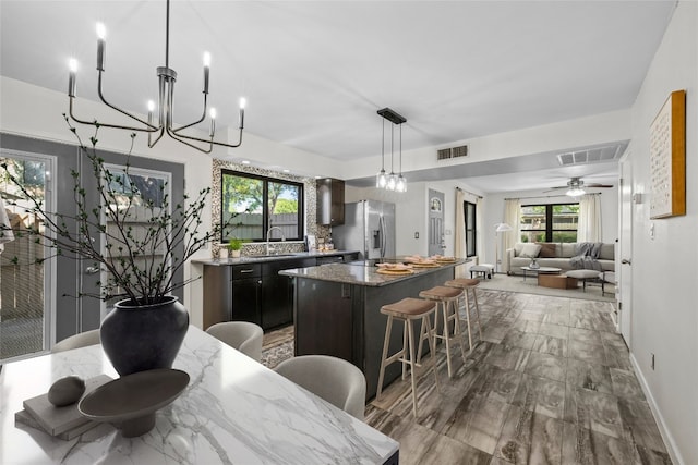 906 E Village Ln, Austin, TX 78758 - kitchen featuring stainless steel fridge with ice dispenser, a center island, a breakfast bar area, dark stone countertops, and open floor plan