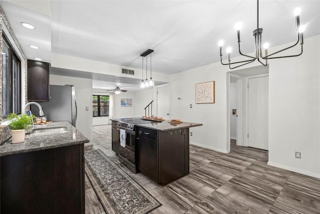 906 E Village Ln, Austin, TX 78758 - kitchen featuring appliances with stainless steel finishes, a kitchen island, dark stone countertops, a ceiling fan, and decorative light fixtures