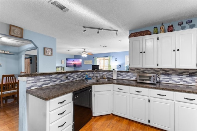 kitchen with a toaster, a peninsula, visible vents, dishwasher, and a sink