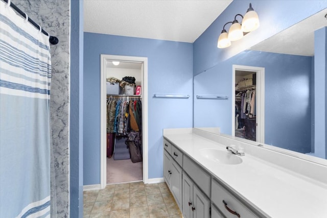 full bathroom with a textured ceiling, vanity, baseboards, and curtained shower