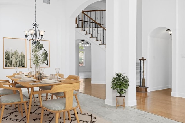 15408 Prestancia Dr, Austin, TX 78717 - dining room featuring arched walkways, a chandelier, a towering ceiling, stairs, and light wood-type flooring