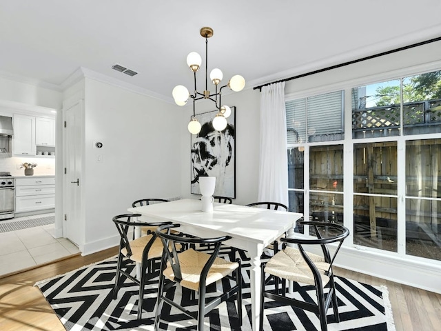 2610 Jefferson St, Austin, TX 78703 - dining area featuring crown molding, light wood-style floors, and a chandelier