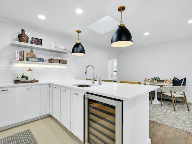 2610 Jefferson St, Austin, TX 78703 - kitchen featuring wine cooler, ornamental molding, a peninsula, light countertops, and white cabinetry