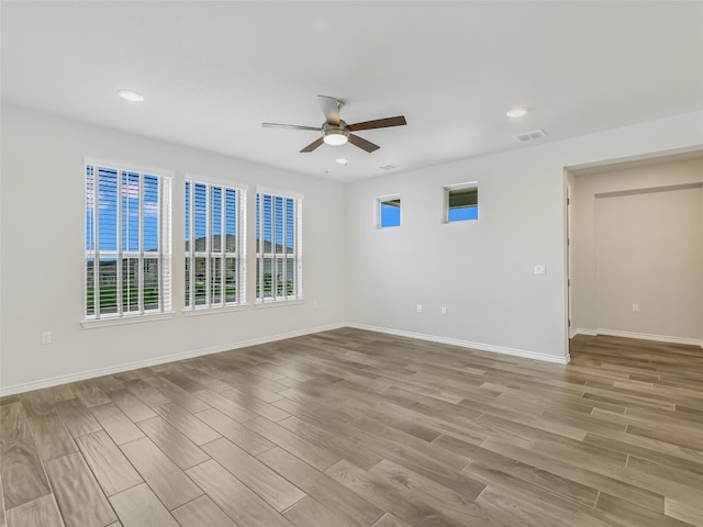 unfurnished room featuring wood finished floors, visible vents, ceiling fan, and a healthy amount of sunlight