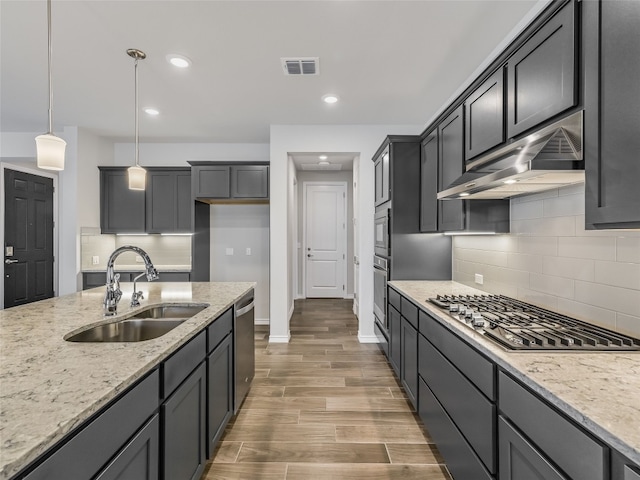 kitchen with stainless steel appliances, a sink, visible vents, baseboards, and under cabinet range hood