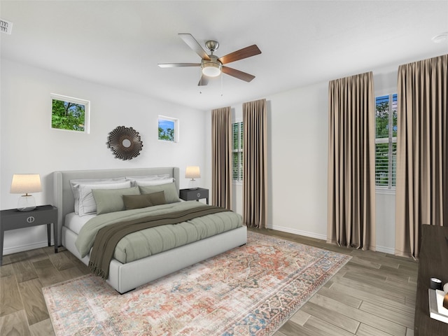 bedroom with light wood-style floors, visible vents, a ceiling fan, and baseboards
