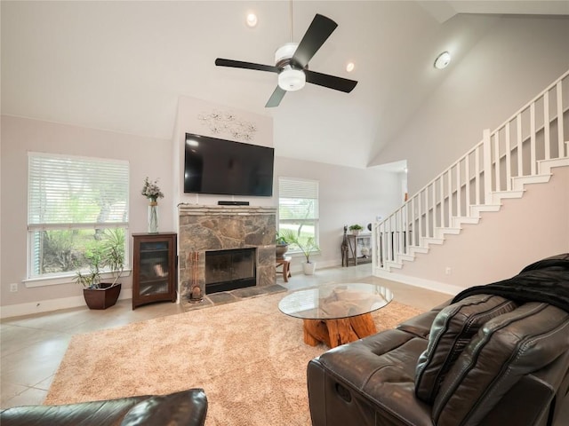 tiled living area with high vaulted ceiling, a fireplace, a ceiling fan, stairs, and baseboards