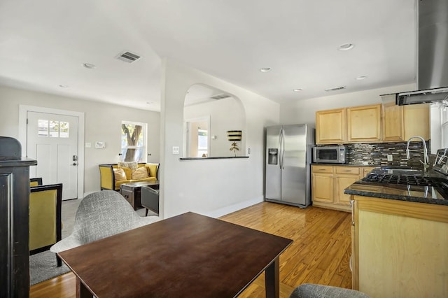 512 Bouldin Ave, Austin, TX 78704 - kitchen featuring appliances with stainless steel finishes, light brown cabinetry, backsplash, light wood-type flooring, and arched walkways