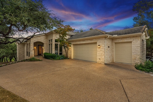 2305 Barton Creek Blvd Unit 36, Austin, TX 78735 - view of front of home with stone siding, concrete driveway, an attached garage, and a tiled roof