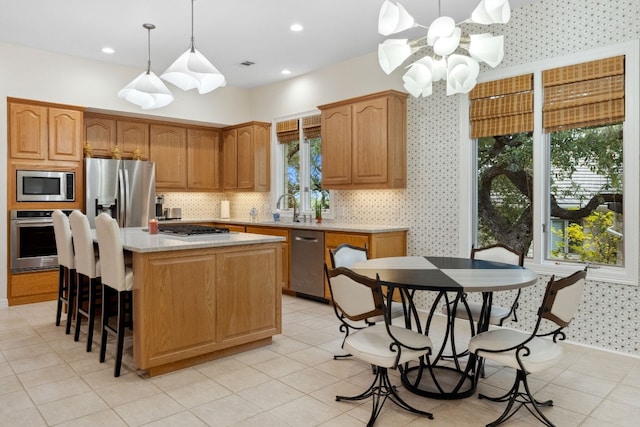 2305 Barton Creek Blvd Unit 36, Austin, TX 78735 - kitchen with stainless steel appliances, light countertops, a center island, decorative light fixtures, and a sink
