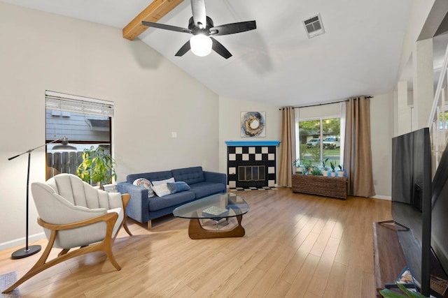 living area with light wood-style flooring, a ceiling fan, a tiled fireplace, and baseboards