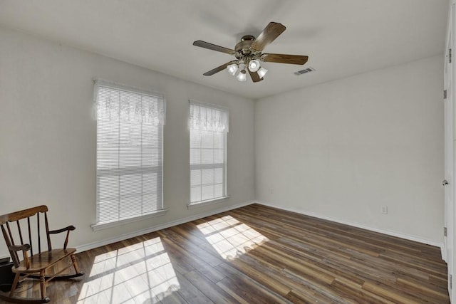 empty room with a ceiling fan, baseboards, dark wood finished floors, and visible vents