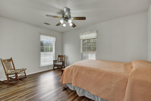 bedroom with ceiling fan, visible vents, baseboards, and wood finished floors