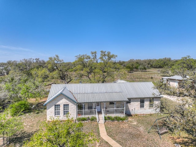 single story home with a porch, metal roof, and stone siding