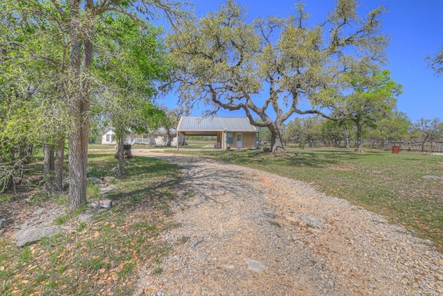 view of front facade with a front yard, metal roof, and driveway