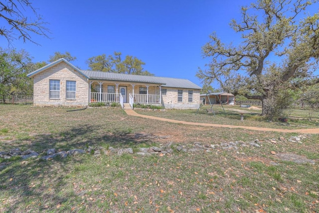 ranch-style home with a front yard, a porch, stone siding, and metal roof
