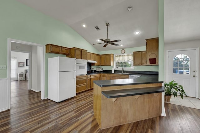 kitchen featuring ceiling fan, dark countertops, white appliances, a peninsula, and dark wood finished floors