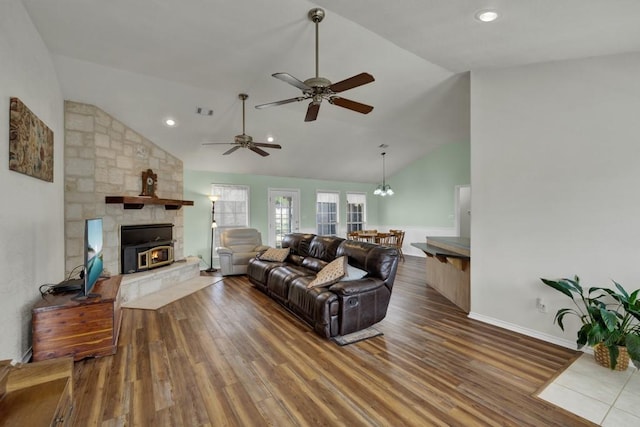 living area featuring ceiling fan with notable chandelier, high vaulted ceiling, a fireplace, visible vents, and wood finished floors