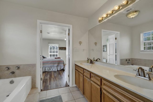 ensuite bathroom with tile patterned floors, a sink, and plenty of natural light