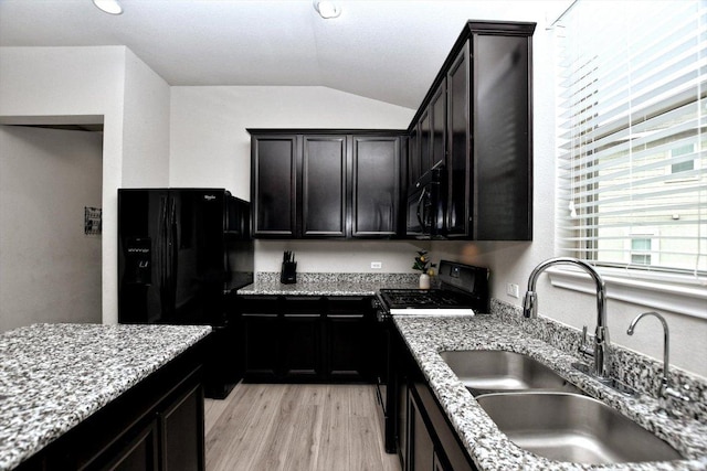 5741 Porano Cir, Round Rock, TX 78665 - kitchen featuring black appliances, vaulted ceiling, light wood-style flooring, light stone counters, and dark cabinetry
