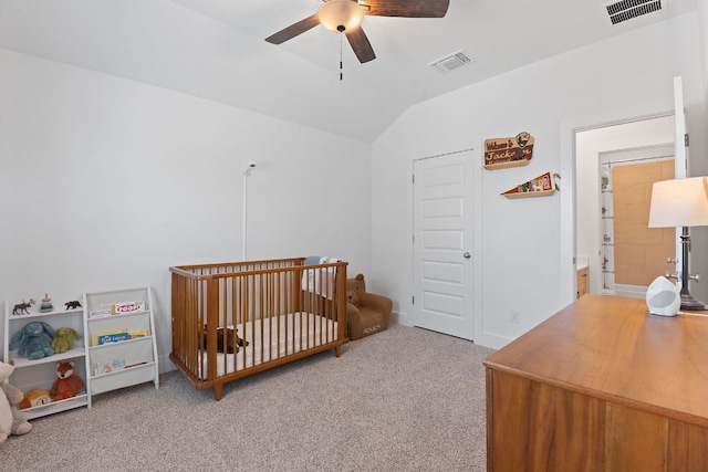 carpeted bedroom with a nursery area, lofted ceiling, a ceiling fan, and visible vents
