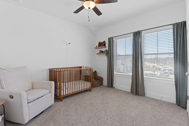 bedroom with vaulted ceiling, a ceiling fan, carpet flooring, and a crib