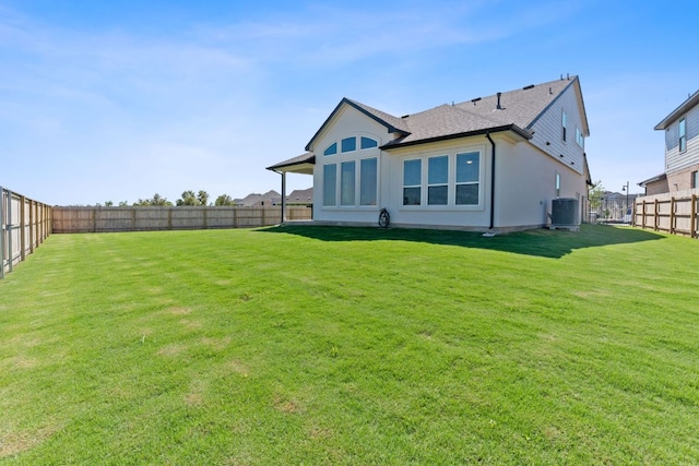 rear view of property featuring roof with shingles, a fenced backyard, central air condition unit, a yard, and stucco siding