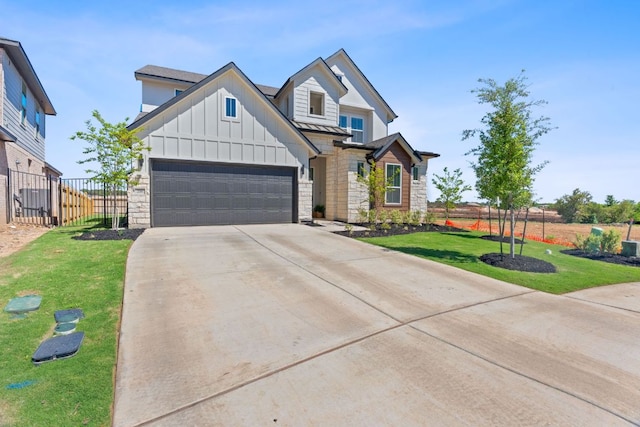modern farmhouse featuring concrete driveway, a front lawn, stone siding, board and batten siding, and fence