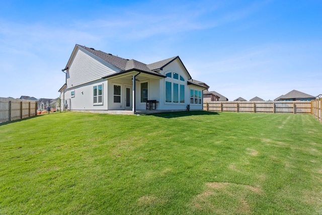 rear view of property featuring stucco siding, a fenced backyard, a yard, and a patio