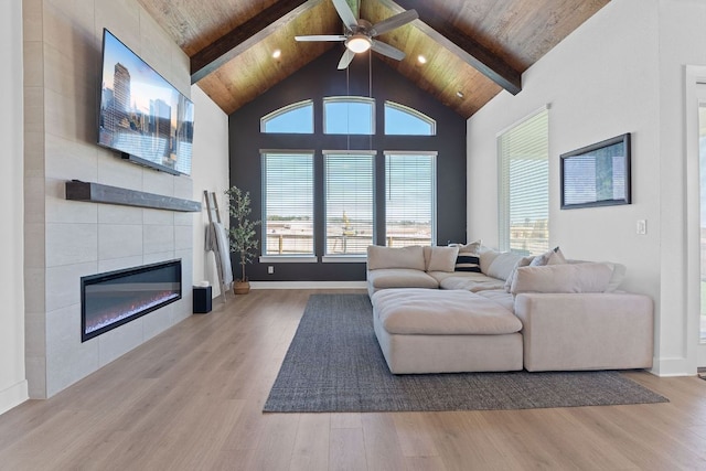 living area with beamed ceiling, a tile fireplace, wood finished floors, and ceiling fan