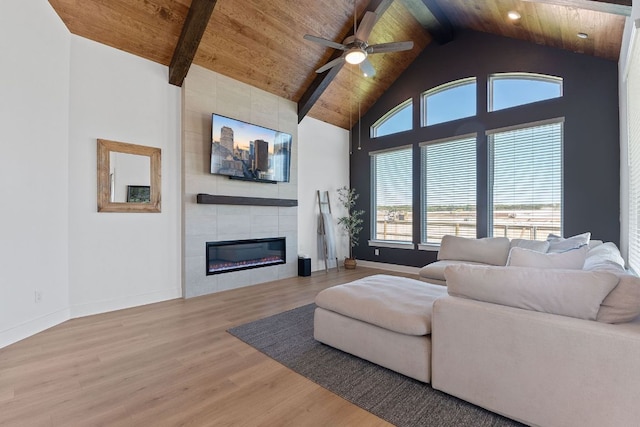 living room with a tile fireplace, wood finished floors, wooden ceiling, high vaulted ceiling, and ceiling fan