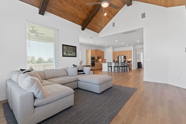 living room featuring light wood-style floors, visible vents, a ceiling fan, and beam ceiling