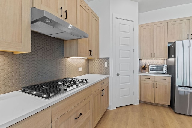 kitchen featuring light brown cabinets, under cabinet range hood, and appliances with stainless steel finishes