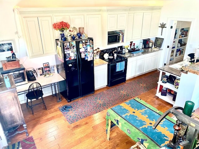 156 Lazy Leaf Ln, Wimberley, TX 78676 - kitchen featuring black appliances, wood finished floors, and white cabinets
