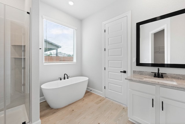 bathroom featuring vanity, wood finished floors, a stall shower, and a freestanding tub