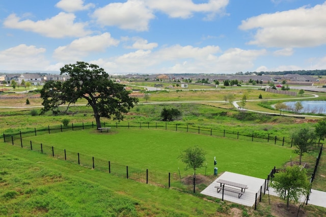 view of property's community with fence, a rural view, and a lawn