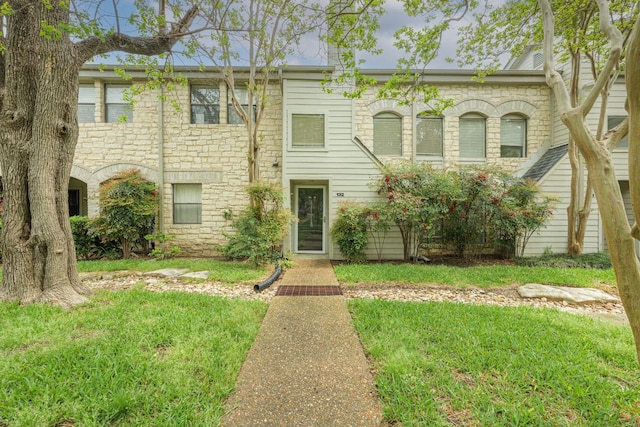 multi unit property featuring a front lawn and stone siding