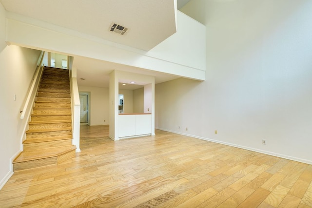 unfurnished living room with light wood-style flooring, visible vents, baseboards, recessed lighting, and stairs