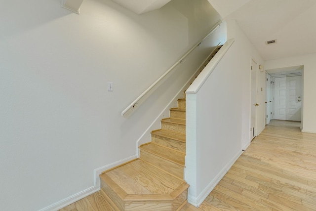 stairs with baseboards, visible vents, and wood finished floors