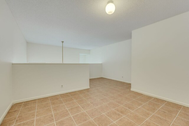 unfurnished room featuring a textured ceiling and baseboards