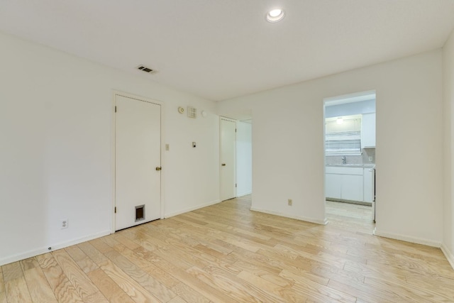 unfurnished room featuring baseboards, visible vents, light wood-type flooring, and recessed lighting