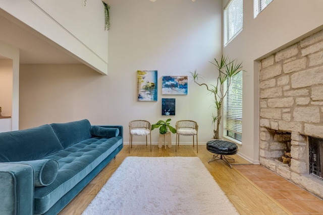 9226 Jollyville Rd Unit 132, Austin, TX 78759 - living room with a stone fireplace, a high ceiling, wood finished floors, and baseboards
