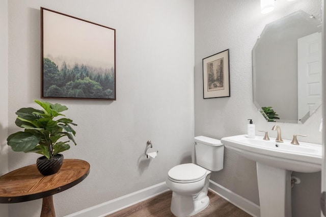 bathroom with toilet, wood finished floors, and baseboards