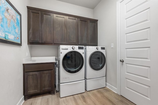 clothes washing area featuring independent washer and dryer, light wood-style floors, baseboards, and cabinet space
