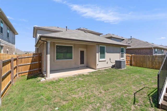 back of property with central air condition unit, a patio, a lawn, and a fenced backyard