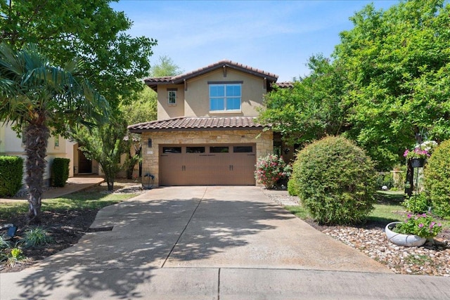 mediterranean / spanish house with a garage, concrete driveway, a tiled roof, and stone siding