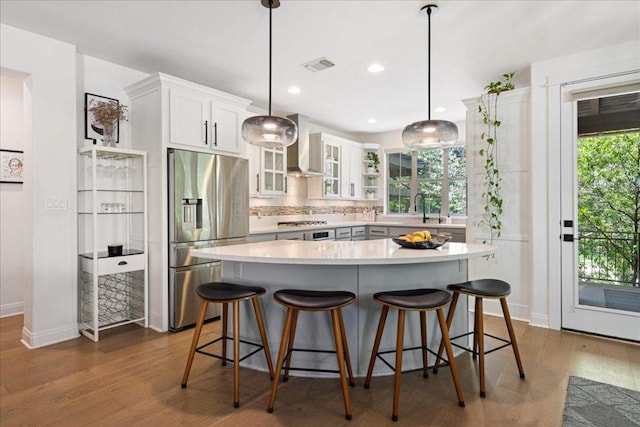 15213 Falconhead Grove Loop, Austin, TX 78738 - kitchen featuring stainless steel fridge, wall chimney range hood, tasteful backsplash, glass insert cabinets, and dark wood-style floors