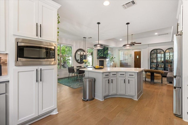 15213 Falconhead Grove Loop, Austin, TX 78738 - kitchen with appliances with stainless steel finishes, light wood-style flooring, light countertops, pendant lighting, and recessed lighting